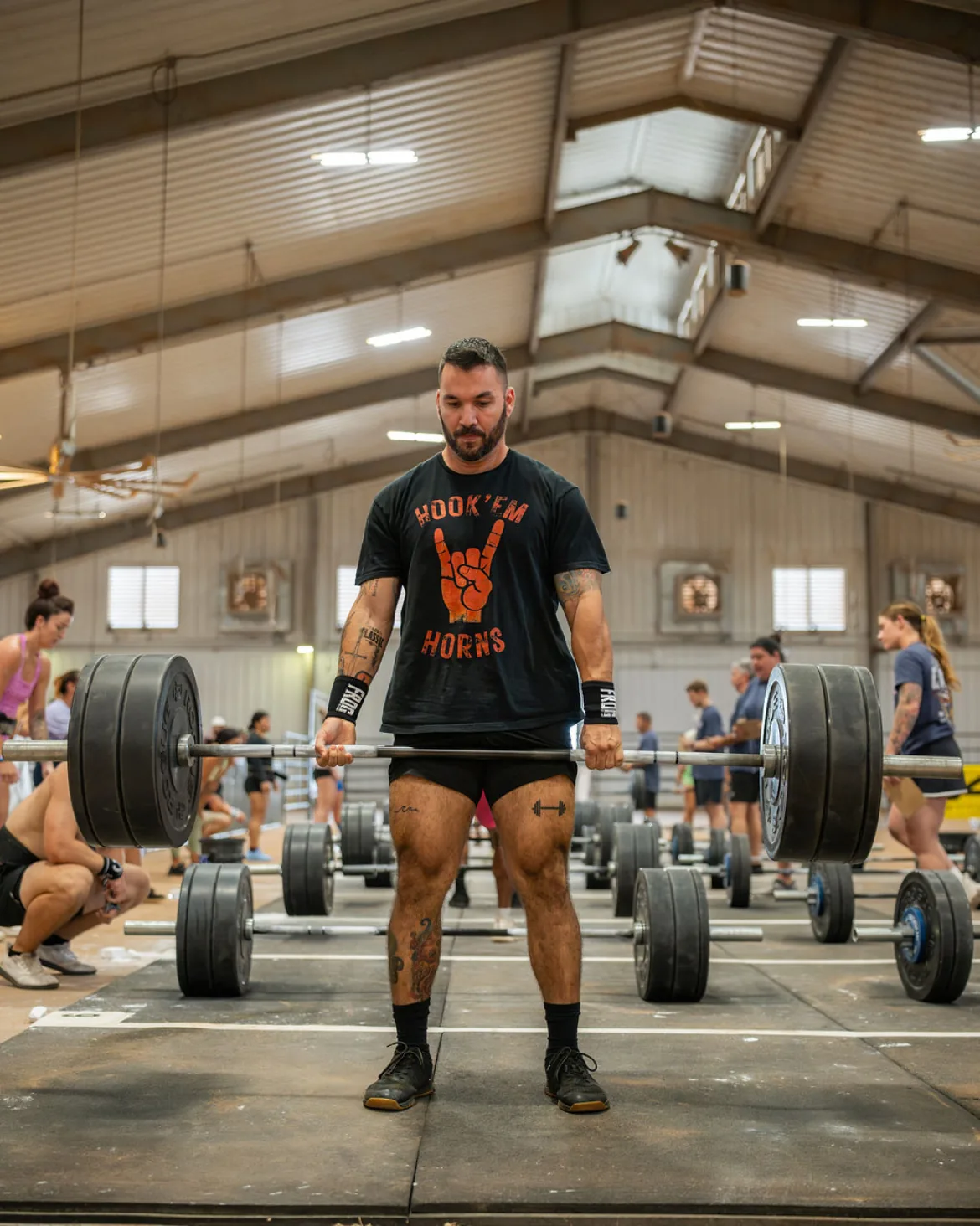 Frankie standing over a loaded barbell mid-deadlift at a CrossFit competition — the work starts here